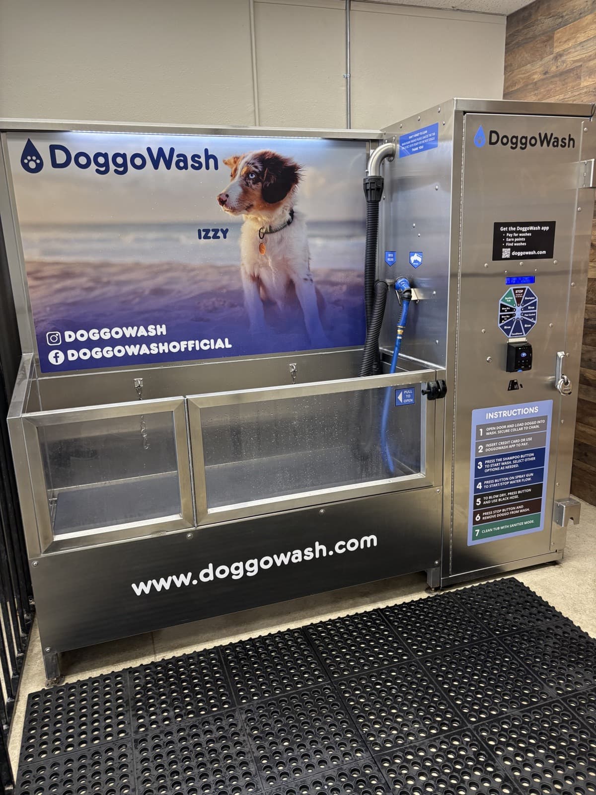 A DoggoWash self-serve dog wash station with a stainless tub, spray nozzle and instruction panel